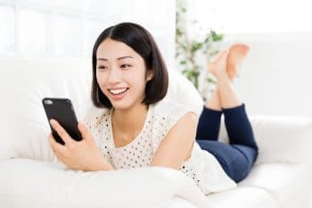 Frau mit Smartphone auf der Couch